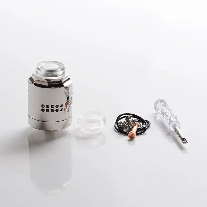 A disassembled silver metallic vape tank or atomizer shown with its clear plastic cap, small clear piece, black cord, copper coil, and a clear-handled screwdriver on a white reflective surface.