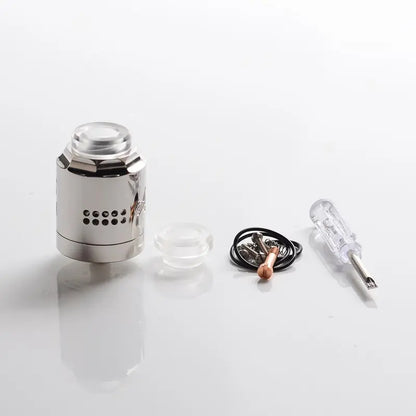 A disassembled silver metallic vape tank or atomizer shown with its clear plastic cap, small clear piece, black cord, copper coil, and a clear-handled screwdriver on a white reflective surface.