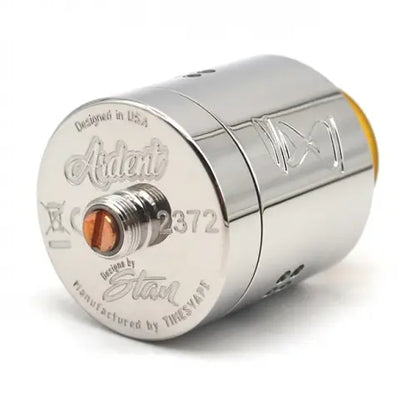 A polished chrome vape coil assembly with engraved branding and technical markings, featuring a small copper-coloured centre contact and a yellow accent at one end, photographed on a white background.